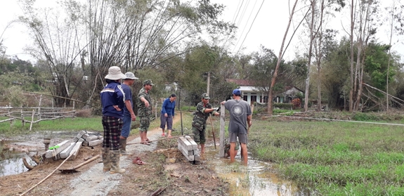 Cán bộ Đoàn Kinh tế-Quốc phòng 516 giúp bà con dựng trụ bê tông chuẩn bị rào lưới B40 khu vực trồng hoa thí điểm.